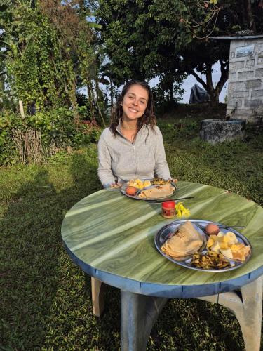 een vrouw die aan een tafel zit met een bord eten bij Mountain View Eco Farm in Rānīpauwa
