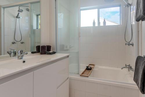 a white bathroom with a tub and a sink at Sunset Waters 12 on Hamilton Island by HamoRent in Hamilton Island