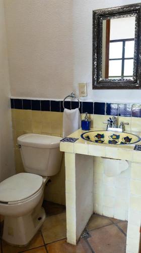 ein Badezimmer mit Toilette, Waschbecken und Spiegel in der Unterkunft Hotel Integra Tepoztlán in Tepoztlán