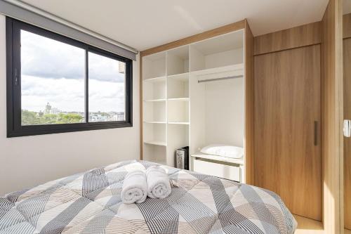 ein Schlafzimmer mit einem Bett und einem großen Fenster in der Unterkunft Edifício Smart Home | Gonzaga Stays in Curitiba