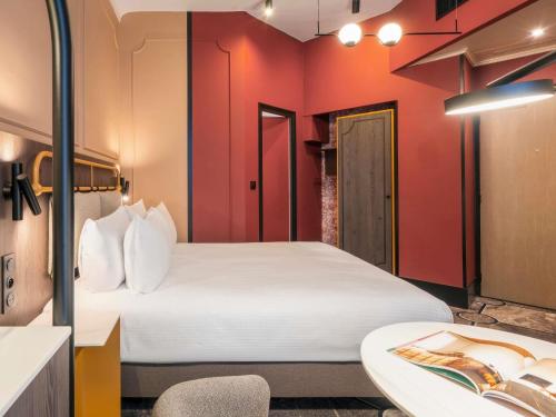 a hotel room with a bed and a bathroom at Grand Hotel des Brotteaux Lyon Ctre - Handwritten Collection in Lyon