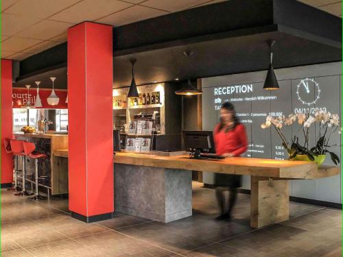 a woman standing at a counter in a restaurant at Ibis Saint-Genis-Pouilly Genève in Saint-Genis-Pouilly