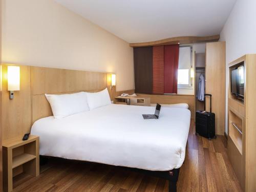 a hotel room with a large white bed and a television at ibis Lyon Est Chaponnay in Chaponnay