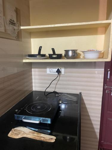 a stove in a kitchen with some pans on a shelf at Sri padha vallabha serenity homestay in Pithāpuram