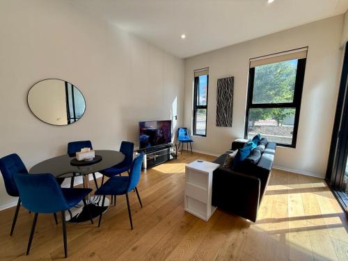 a living room with a table and blue chairs at Luxe 2BR Executive Apartment Kingston Pool Parking WiFi BBQ Wine in Kingston