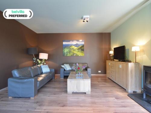 a living room with a couch and a tv at Durbuy Villa with Sauna in Durbuy