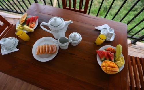 a table with plates of food and cups of orange juice at Ella Ninestars Lodge in Ella