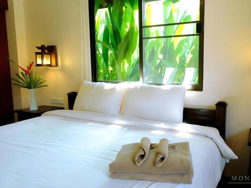 a bedroom with a bed with two slippers on it at Monn Phu Phrai in Ban Pong