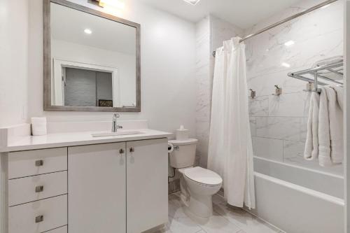 a white bathroom with a toilet and a mirror at The Saddlery - Headliner - Walk to Broadway in Nashville