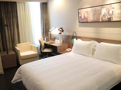 Jinjiang Inn Select Xining West Wusi Road New Hualian Square في شينينغ: غرفة في الفندق بسرير وكرسي ومكتب