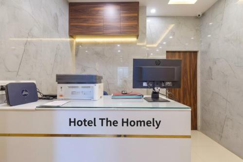德拉敦The Homely Homestay Near Pacific Mall Dehradun的酒店大堂里有一台电脑，柜台上摆着一台电脑。