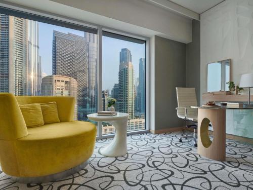 un soggiorno con sedia gialla e una grande finestra di Sofitel Dubai Downtown a Dubai