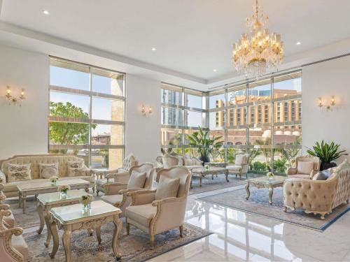 a living room with couches and tables and windows at Sofitel Abu Dhabi Corniche in Abu Dhabi