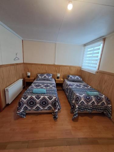 a room with two beds and a window at Casa Hospedaje Costanera in Puerto Natales