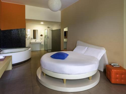 a bedroom with a white bed and a bath tub at ibis Styles Catania Acireale in Acireale