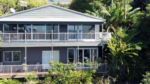 a blue house with a large balcony and trees at Point View - 'amazing Views =& Location=' in Avoca Beach
