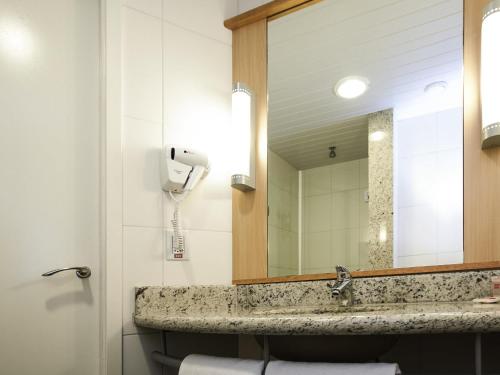 a bathroom with a sink and a mirror at ibis Cascavel in Cascavel