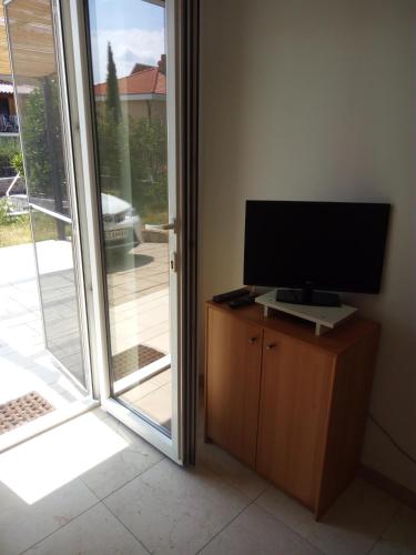 a television sitting on a cabinet next to a sliding glass door at Apartments Pronavtik in Piran