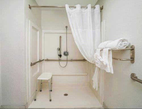 Un baño blanco con ducha y taburete. en The Windstar Hotel - Emerald Isle, Swansboro, en Cedar Point