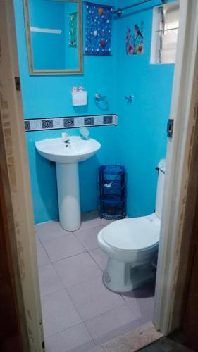 a blue bathroom with a toilet and a sink at Titanic's Nipa Hut in Moalboal