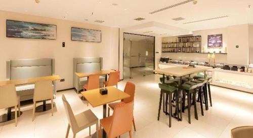 a restaurant with tables and chairs in a room at City Comfort Inn Jiyuan Jishui Avenue Jigang in Jiyuan