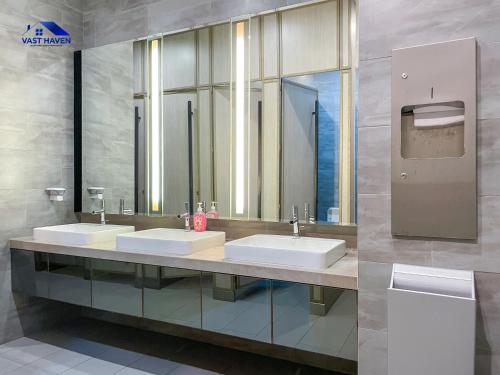 une salle de bain avec deux lavabos et deux miroirs dans l'établissement 188 Suites KLCC by VastHaven, à Kuala Lumpur