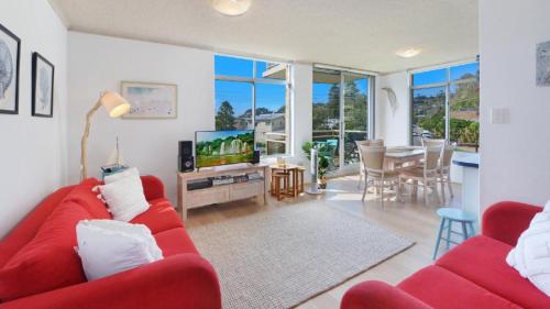 a living room with a red couch and a tv at Seaview 7 - Prime Position Beachside Holiday in Avoca Beach