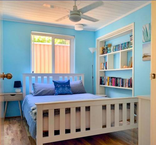 - une chambre avec des murs bleus et un lit avec une étagère dans l'établissement Falcon Bay Family Retreat, à Falcon