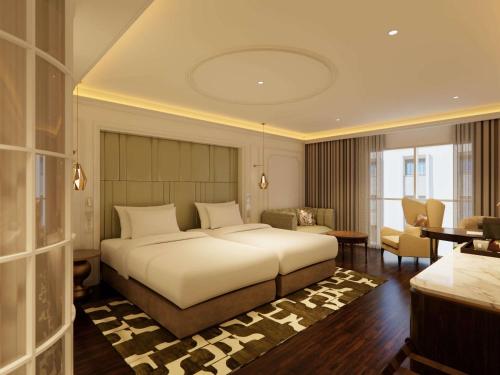 a bedroom with a large bed and a living room at Hotel de l'Opera Hanoi - MGallery in Hanoi