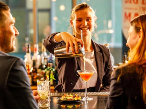 a woman bartender making a drink at a bar at Novotel London Blackfriars in London