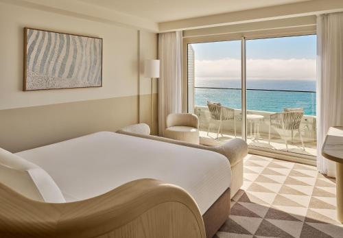 a hotel room with a bed and a view of the ocean at InterContinental Sydney Coogee Beach by IHG in Sydney