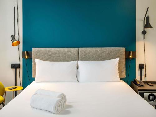 a bed with white pillows and a blue wall at ibis London Blackfriars in London