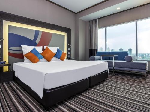 a hotel room with a large bed and a couch at Novotel Bangkok IMPACT in Nonthaburi