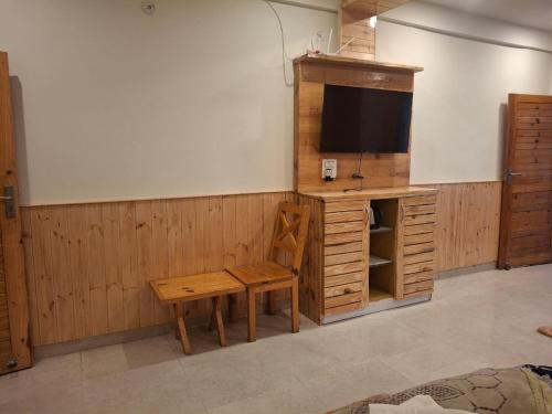 Habitación con TV, mesa y banco. en lake & woods-a boutique lakeview property, en Bhimtal