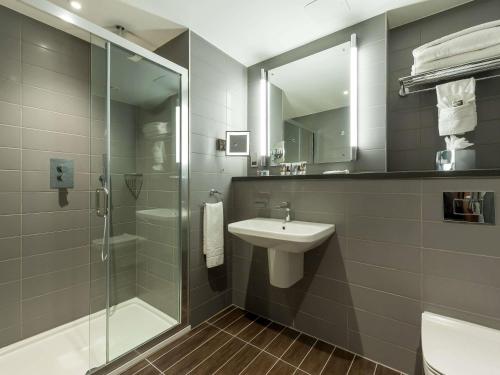 een badkamer met een glazen douche en een wastafel bij Mercure London Paddington Hotel in Londen