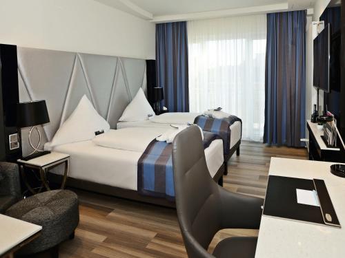 ein Hotelzimmer mit zwei Betten und einem Stuhl in der Unterkunft Mercure Hotel Kaiserhof City Center in Frankfurt am Main