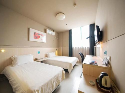 a hotel room with two beds and a desk at Jinjiang Inn Nantong Gongnong Road in Nantong