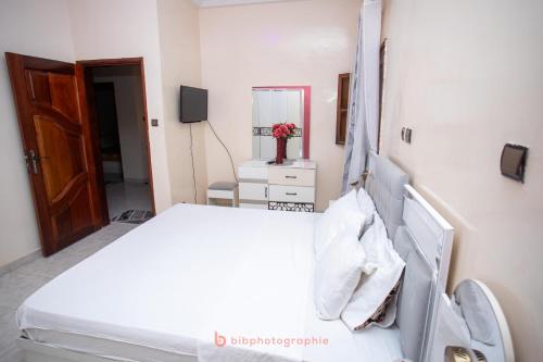 Cabral residence في Guediawaye: غرفة نوم بيضاء مع سرير ومرآة