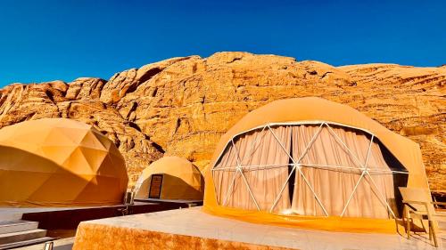 a group of tents in front of a rocky mountain at Wadi Rum Desert Life in Wadi Rum