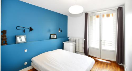 a blue bedroom with a bed and a window at Appart' Montcharmont in Lyon