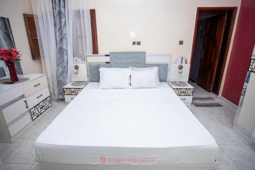 a bedroom with a large white bed in a room at Cabral residence in Guediawaye