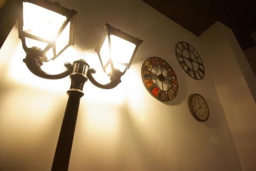 a lamp with three clocks on the wall at All Iron Hostel in Bilbao