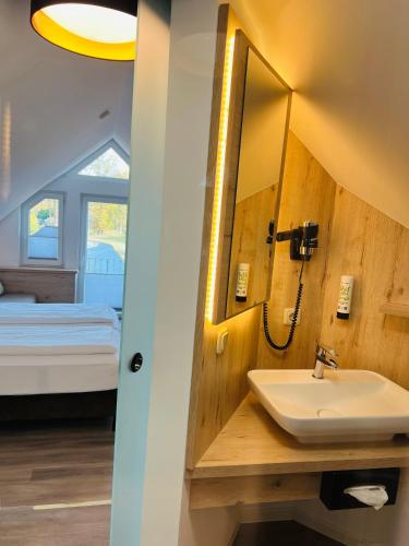 a bathroom with a sink and a mirror and a bed at Hotel Alte Fischerkate in Mödlich