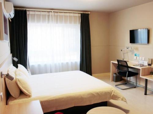 a bedroom with a bed and a desk and a window at Jinjiang Inn Changchun City Hall in Changchun