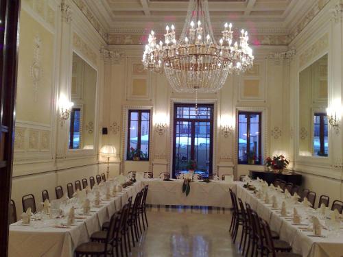 a large room with white tables and chairs and a chandelier at Grand Hotel Plaza & Locanda Maggiore in Montecatini Terme