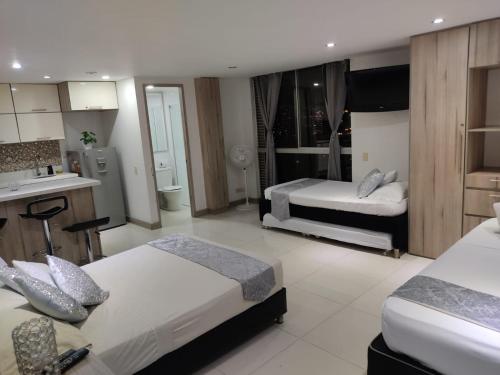 Una habitación de hotel con dos camas y cocina. en ApartaSuite 2 a 3 personas cerca club campestre, en Medellín