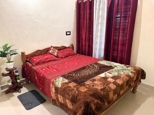 a bedroom with a bed with red sheets and red curtains at Swasthiks Home stay in Sakleshpur