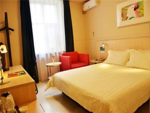 a hotel room with a bed and a red chair at Jinjiang Inn Changchun Renmin Avenue Guilin Road in Changchun