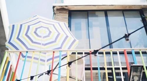 a colorful umbrella sitting on a balcony next to a window at The Sugar Hostel in Ban Sai Ma