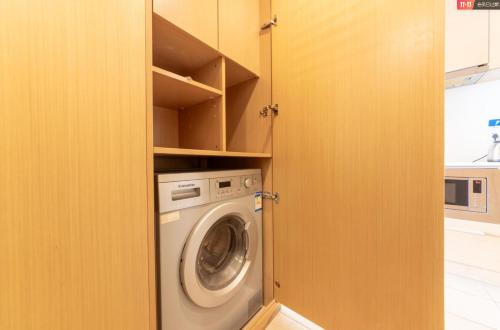 a laundry room with a washing machine in a closet at Qingdao Tinglan Hotel Apartment (Wusi Square Mixc City Branch) in Qingdao